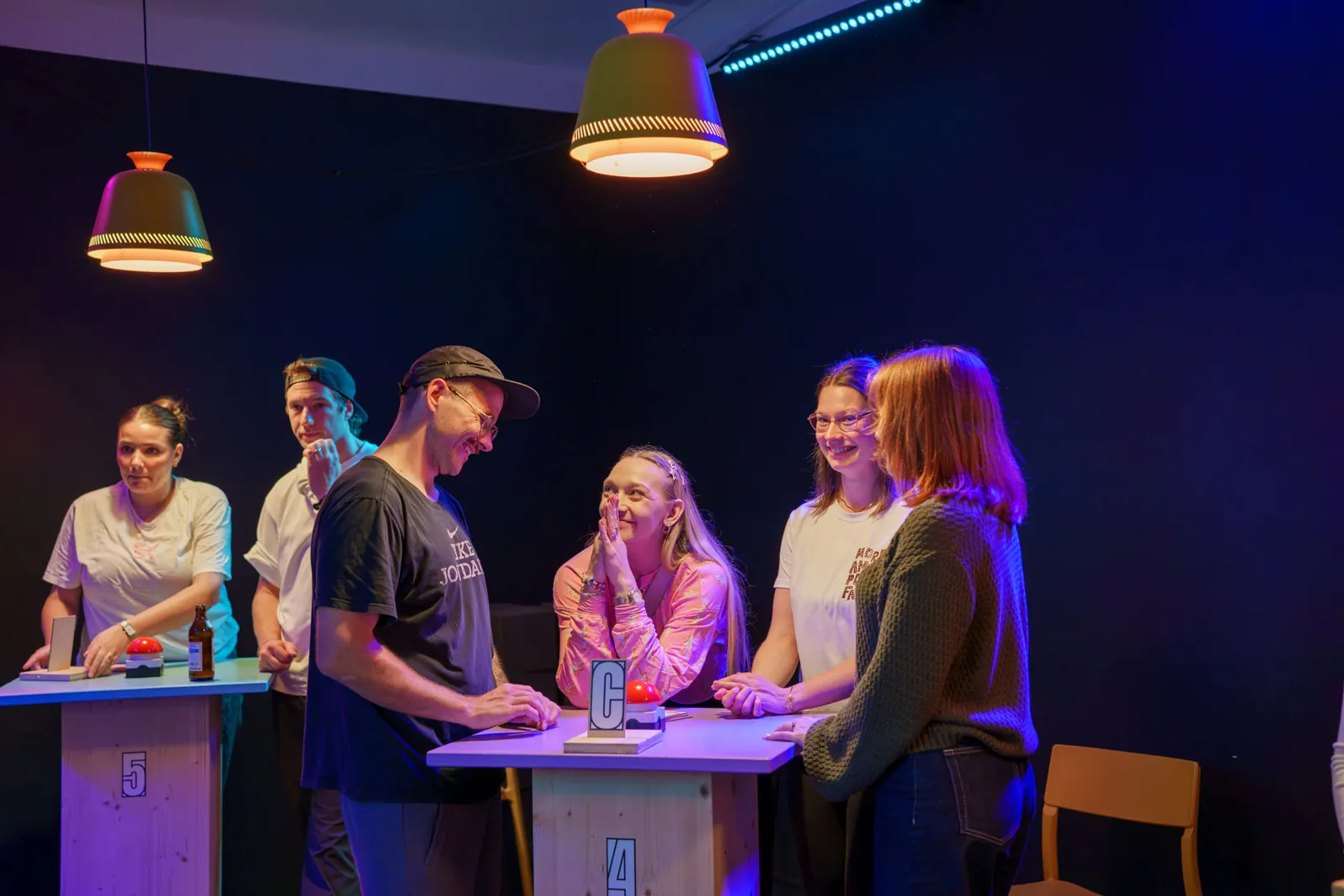 Firmenteam fiebert im Quizraum von The Big Bash am Buzzer-Tisch mit